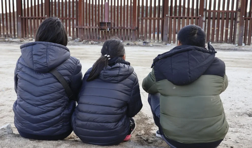 A Chinese family sits in front of a wall on the U.S.-Mexico border in Jacumba Hot Springs, California, January 23, 2024